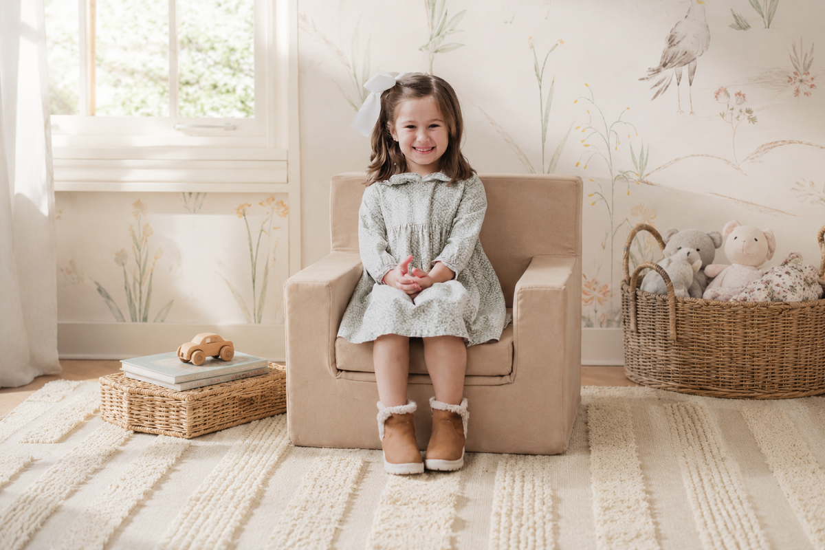 Niña sentada en su sillón infantil personalizado Cubino de color taupé